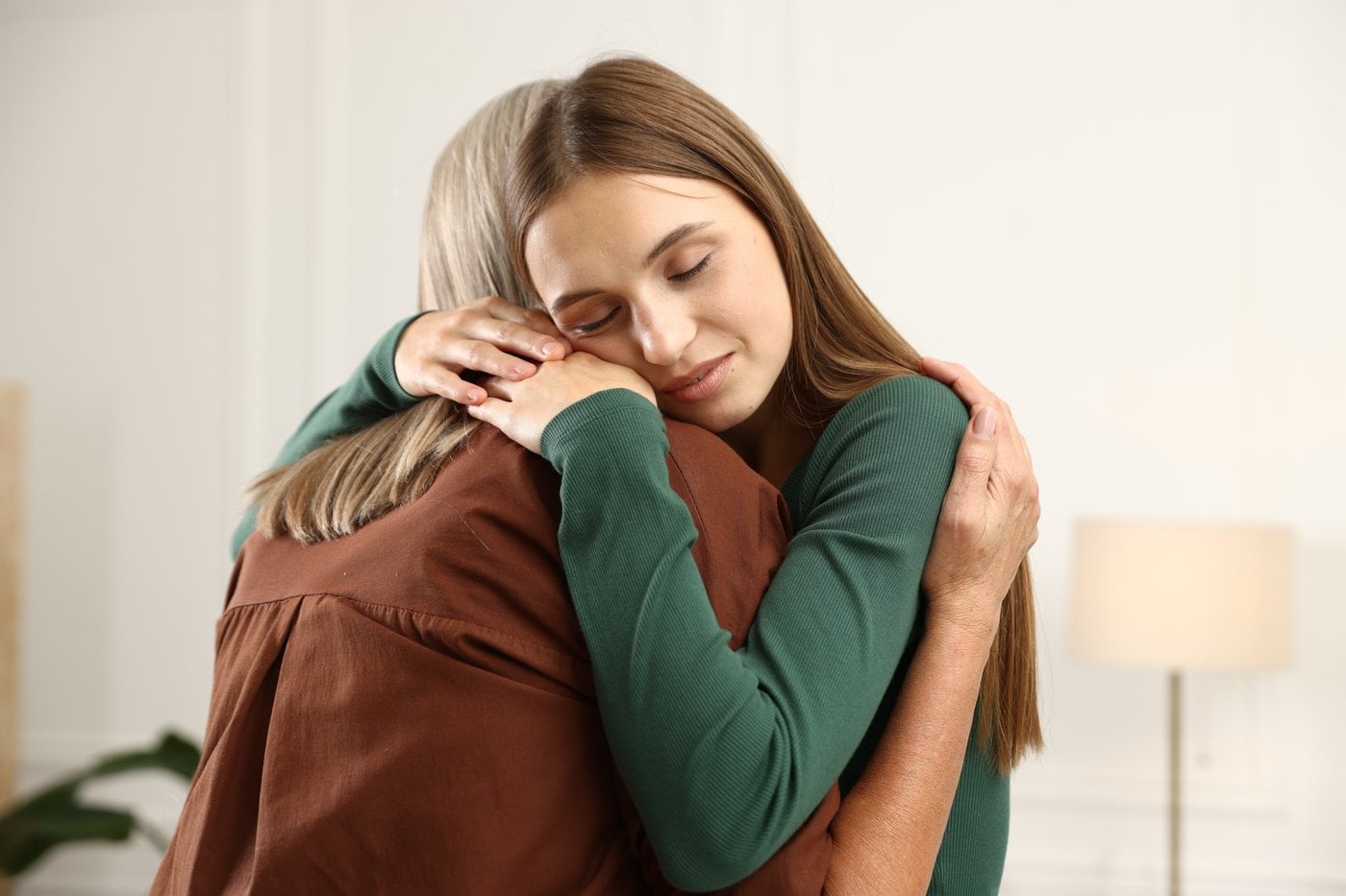 Young woman warmly embracing her elderly mother at home