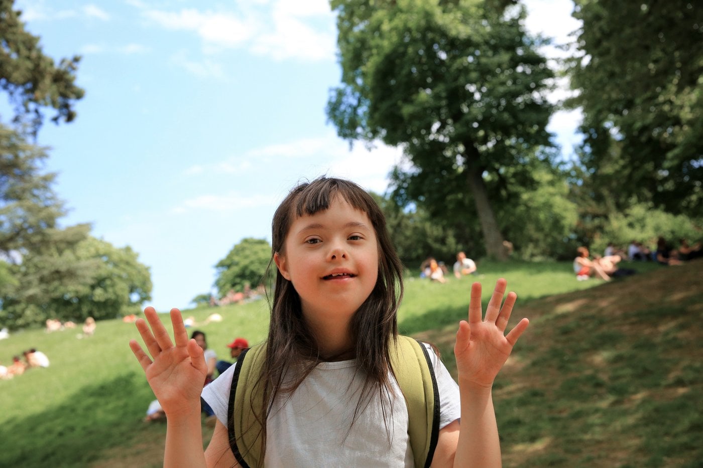 Girl with Down syndrome smiling happily in a sunlit park