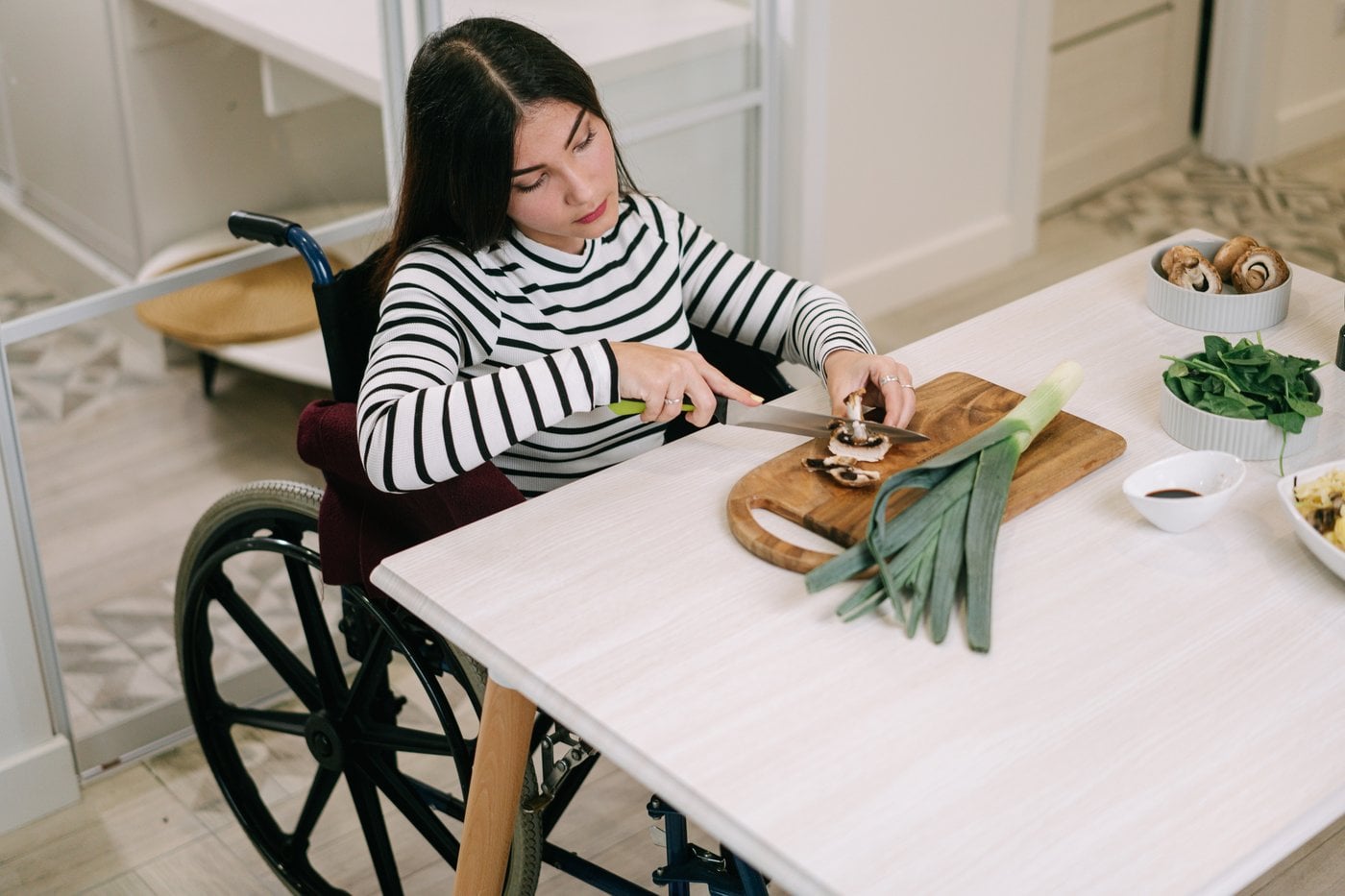 Woman in wheelchair chopping vegetables independently in the kitchen