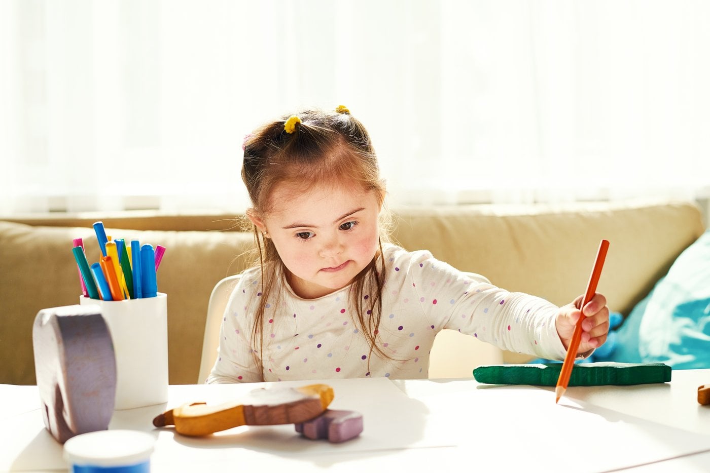 Girl with Down syndrome painting at a table during a creative activity