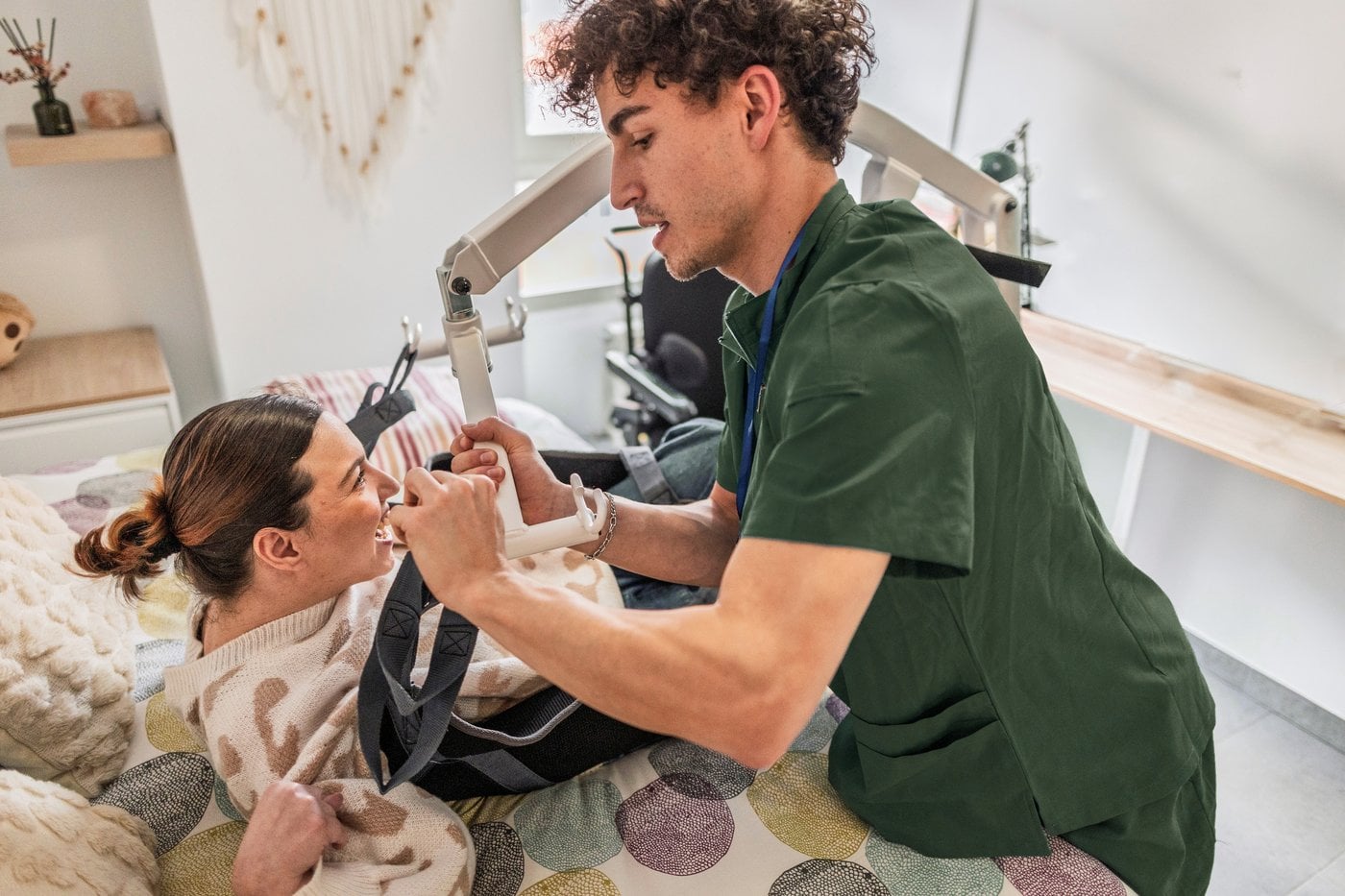 Carer assisting a person with a hoist transfer from bed