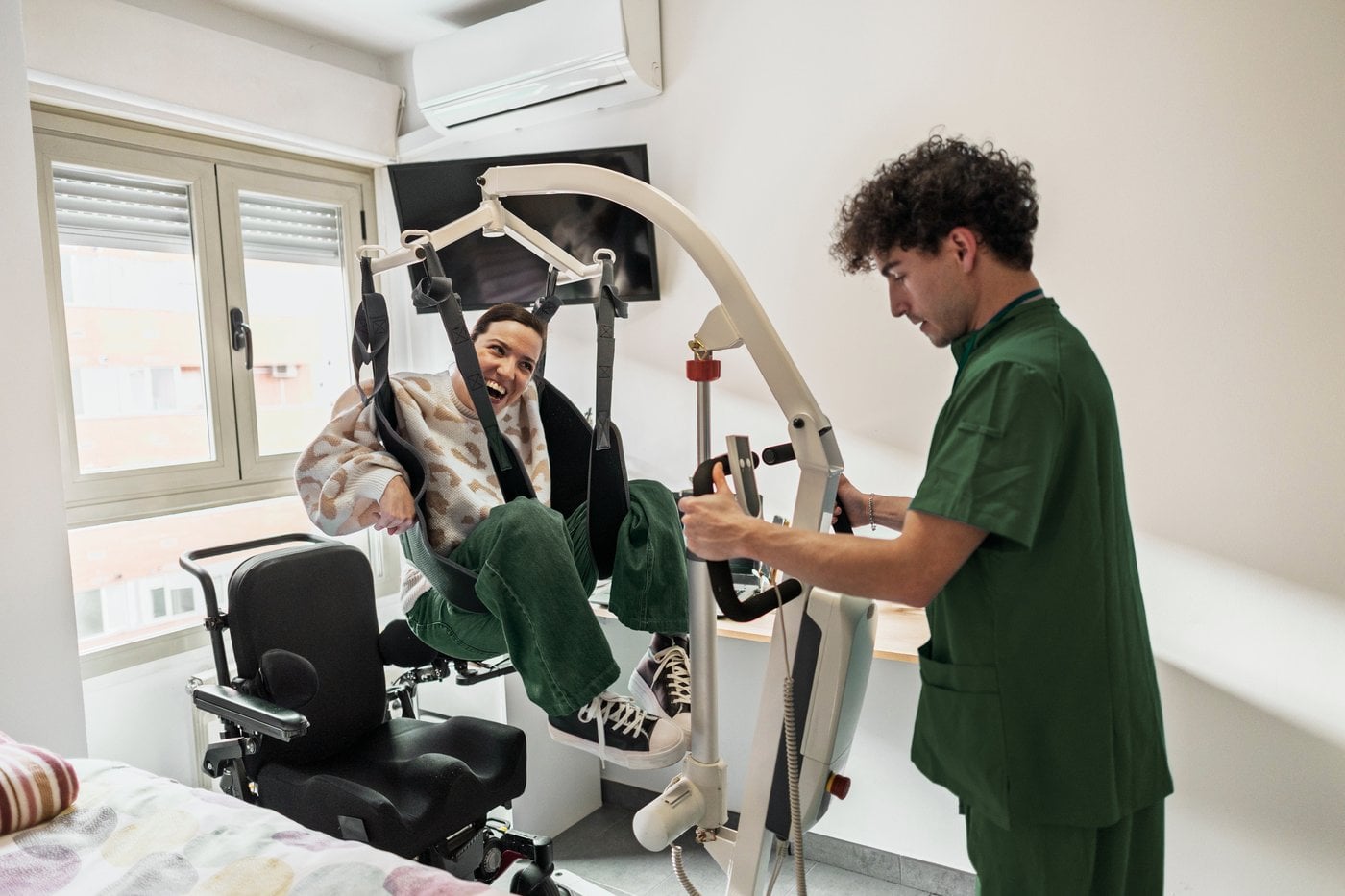 Carer using a ceiling hoist to safely transfer a wheelchair user