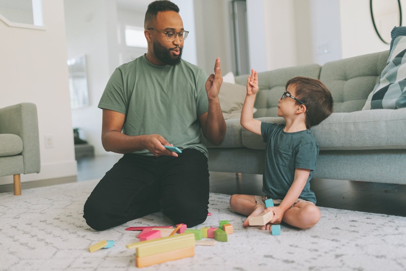 Father and son giving a high-five while playing with building blocks