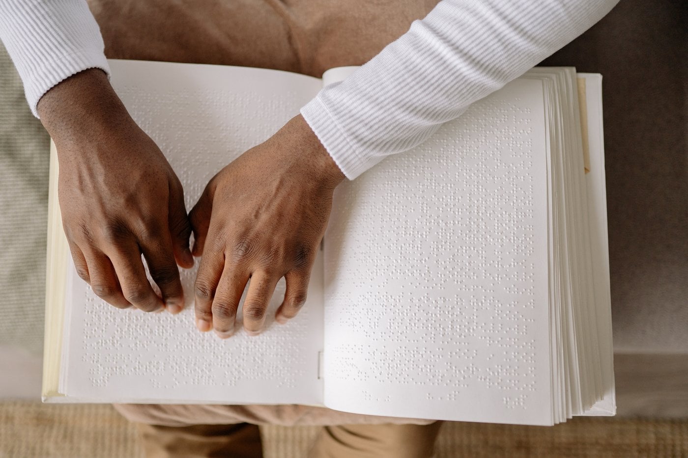 Person reading a braille book at a desk
