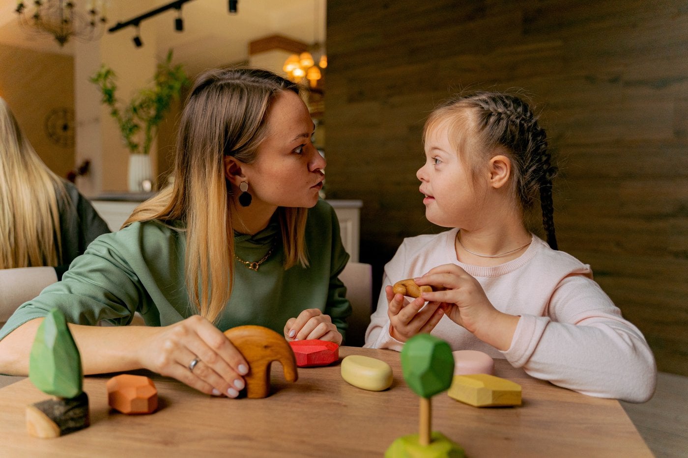 Therapist working with a young girl using wooden toys during a play session